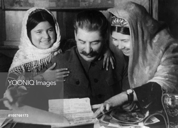 Joseph stalin with two young women from a collective farm in tadjikistan at a conference on cotton farming, january 1935.